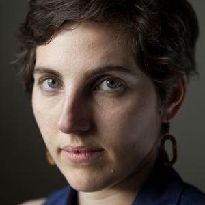 A headshot of Éléonore Goldberg, a white woman with short brown hair, looking straight at the camera against a dark background.