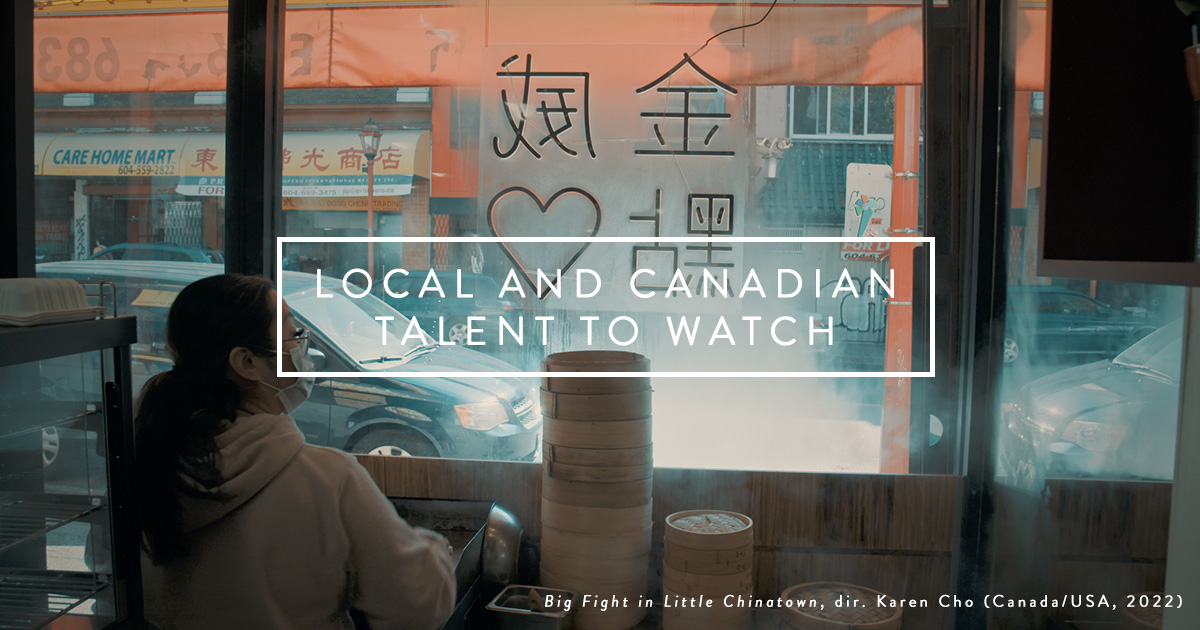 Looking out into the street from within Kam Wai Dim Sum in Vancouver Chinatown, steamed windows and stacks of steaming trays, a woman in a mask looks out the window