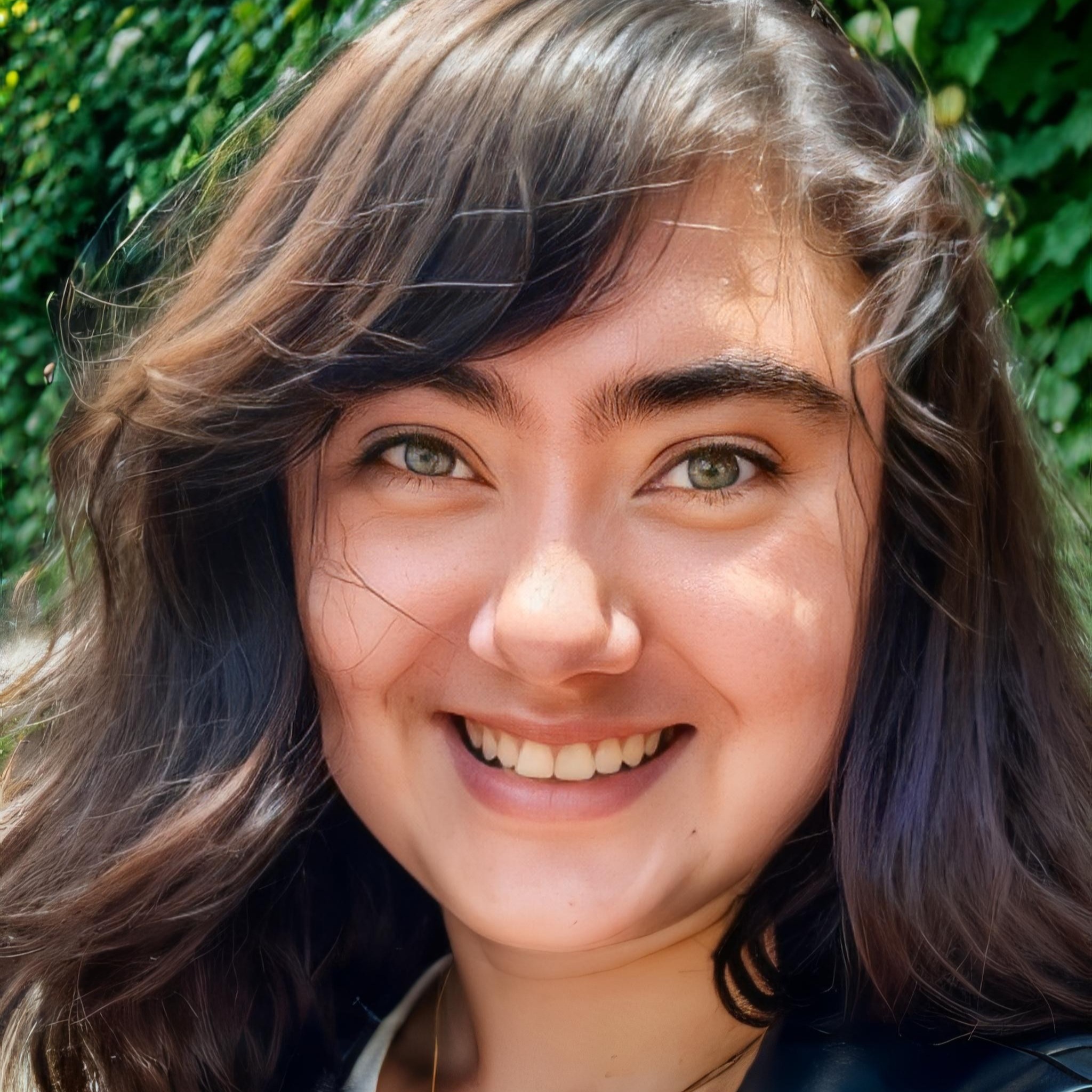 Close-up photo of a person with medium length brown hair and a bright smile.