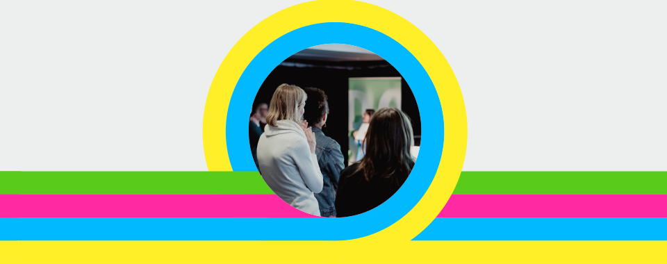 A group of people is seen from behind, framed by colorful concentric circles. Stripes of yellow, green, pink, and blue run horizontally.