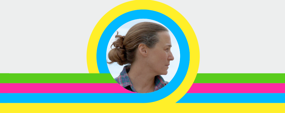 Side profile of a woman with light brown hair in a messy bun, wearing a plaid shirt, centered in a circular frame with bright yellow and blue rings, against a gray background with colorful horizontal green, pink, and blue stripes; contemporary visual identity design.