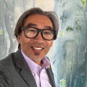 Photo of a man in glasses wearing a grey suit.