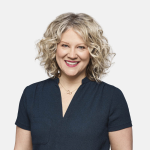 Headshot of a blond woman with mid-length curly hair.